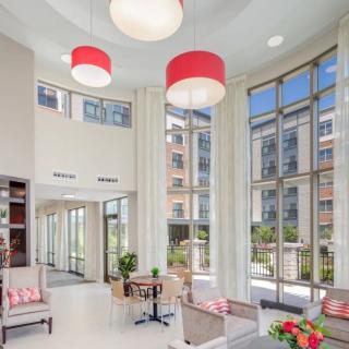 A modern lobby featuring large windows and red-accented lighting, offering ample natural light and comfortable seating.
