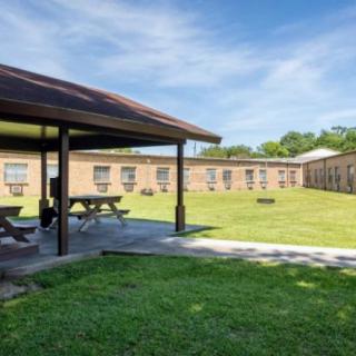A courtyard with picnic tables and a well-maintained lawn surrounded by brick buildings.