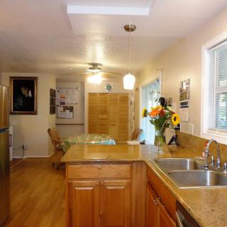 A bright, inviting kitchen with wooden cabinets and floors, featuring a central island and dining area.