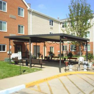 An apartment building entrance with a covered awning and benches.
