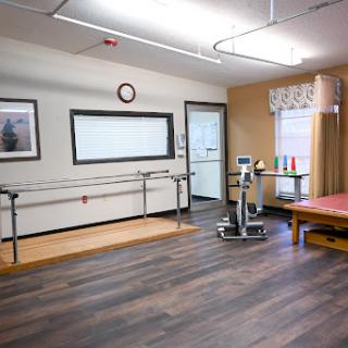 A well-equipped physical therapy room featuring walking bars and exercise equipment, designed for rehabilitation and patient care.