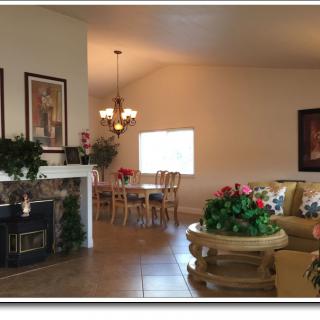 A cozy living room with a connected dining area, featuring a fireplace and indoor plants.