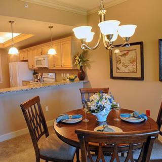 A cozy dining area with a round table set for four, adjacent to an open kitchen.