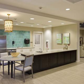 A modern kitchen space featuring a sleek countertop, seating area, and stylish light fixtures.