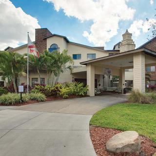 A welcoming building entrance with a driveway and lush landscaping.