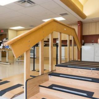 A physical therapy room with equipment and stairs for rehabilitation exercises.