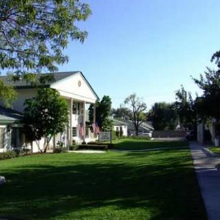 A sunny day view of a residential area with buildings, lush green grass, and trees lining a pathway.