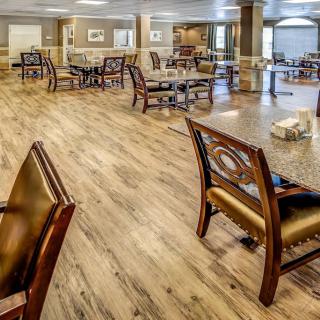 A spacious dining area with wooden flooring and neatly arranged tables and chairs.
