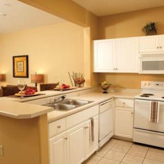 A modern kitchen with white cabinets and appliances, featuring a spacious countertop and sink.
