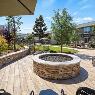 A beautifully landscaped outdoor patio featuring a central fire pit and lush greenery.