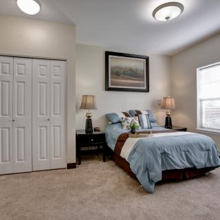 A cozy bedroom with a neatly made bed, two lamps on nightstands, and a framed picture above the headboard.