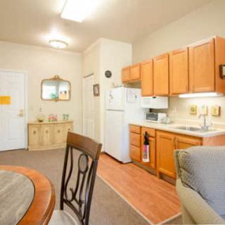 A cozy apartment kitchen and dining area with wooden cabinets and a small dining table.