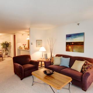 A cozy living room featuring a sofa with cushions, a wooden coffee table, and wall artwork.