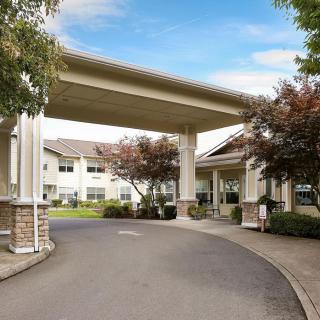 A covered entrance to a residential building with a driveway and landscaped surroundings.