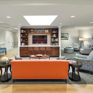 A modern living room with an orange sofa, built-in bookshelves, and a television.