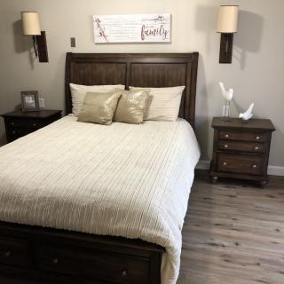 A neatly arranged bedroom with a wooden bed, matching nightstands, and soft lighting.