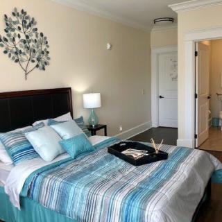 A modern bedroom with a striped bedspread, decorative pillows, and a wall art piece above the headboard.