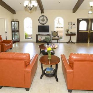 A modern living room with orange chairs, a central coffee table, and a television.
