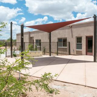 An outdoor area with a shade structure attached to a modern building on a sunny day.