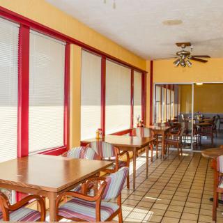 A bright restaurant dining area with large windows and neatly arranged tables and chairs.