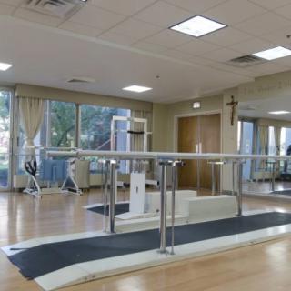 A rehabilitation center equipped with parallel bars and exercise equipment for physical therapy.