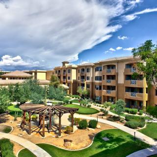 A scenic view of a resort with well-maintained gardens and lush greenery under a cloudy sky.