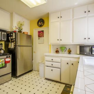 A bright kitchen with white cabinets, stainless steel appliances, and patterned tile flooring.