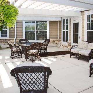 A patio area with wicker furniture and a pergola providing shade.