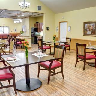 A cozy dining area with neatly arranged tables and chairs, decorated with flowers on each table.