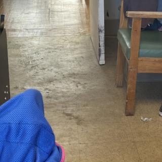 A view of a waiting area with chairs and a floor showing signs of wear.