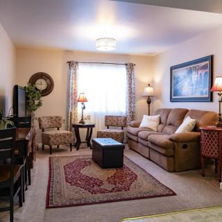 A cozy living room with traditional decor, featuring a comfortable sofa, armchairs, and a coffee table set on a decorative rug.