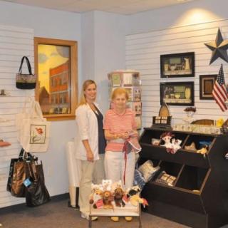 Two people standing in a small shop with various products on display.
