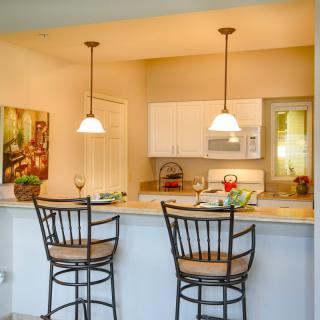 A modern kitchen with a cozy breakfast bar, featuring two elegant bar stools and warm pendant lighting.