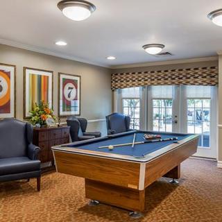 A cozy game room featuring a pool table, comfortable chairs, and vibrant artwork on the walls.