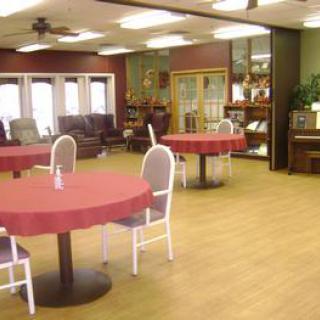A community dining area with round tables covered in red tablecloths and surrounded by chairs.