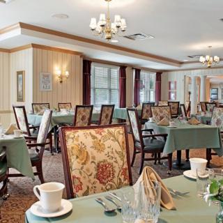 An elegant dining room with tables set for service and patterned chairs.