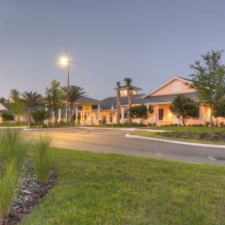 A well-lit building surrounded by trees and grass during the evening.