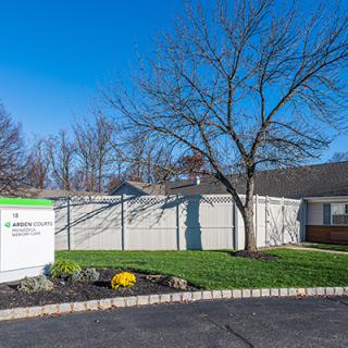 A small building with a sign, tree, and road under a clear blue sky.