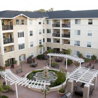 A multi-story apartment complex with a central courtyard featuring a fountain and landscaping.