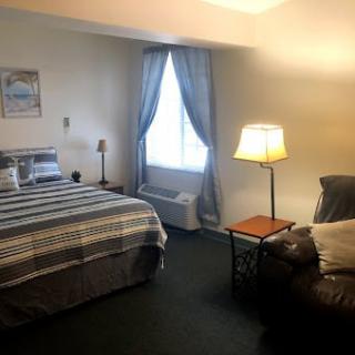 A cozy bedroom featuring a bed with striped bedding, a floor lamp, and a window with curtains.