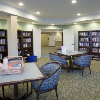 A cozy library reading area with tables, chairs, and bookshelves.