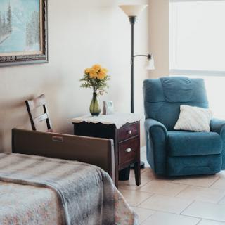 A cozy bedroom featuring a comfortable recliner, floral decor, and warm natural lighting.