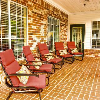A cozy patio with red-cushioned chairs lined up against a brick wall.
