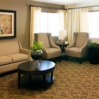A cozy living room with a sofa, armchairs, and a coffee table, decorated with plants and artwork.