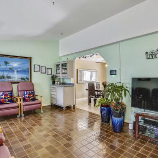 A cozy living room with a television, comfortable seating, and decorative plants.