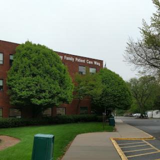 A view of a red brick building surrounded by lush greenery on a cloudy day.