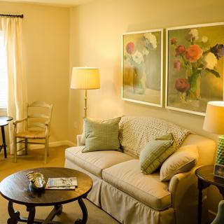 A cozy living room with a comfortable sofa, decorative lamps, and floral artwork on the wall.