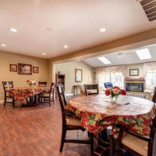 A cozy dining area with tables covered in colorful tablecloths, surrounded by wooden chairs and warm lighting.