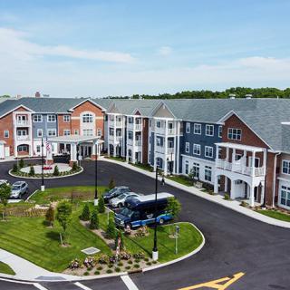A modern residential apartment complex with landscaped gardens and a parking area.