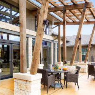 A modern patio area with outdoor seating, featuring wooden beams and a pergola.